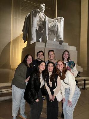 A group of students standing in front of the Lincoln Memorial at night.